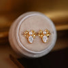 Alice Bow Stud Earrings - Lovely, delicate gold earrings shaped like a stylised bow, punctuated with a tiny pearl in the centre and a sparkling white quartz below.