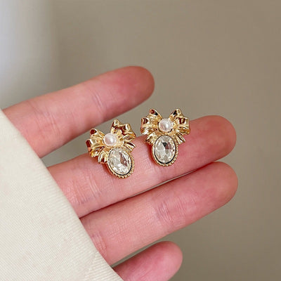 Alice Bow Stud Earrings - Lovely, delicate gold earrings shaped like a stylised bow, punctuated with a tiny pearl in the centre and a sparkling white quartz below.