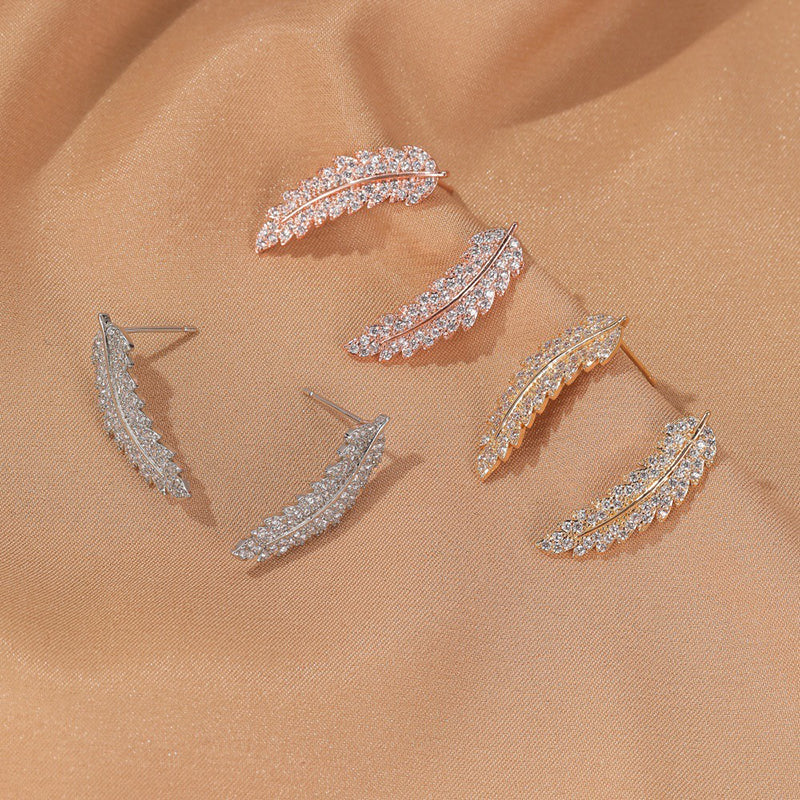 Angelina Feather Crystal Studs Earrings - A tiny stud earring that looks like a stylised feather or fern frond studded with crystals, available in yellow, rose, or white gold.