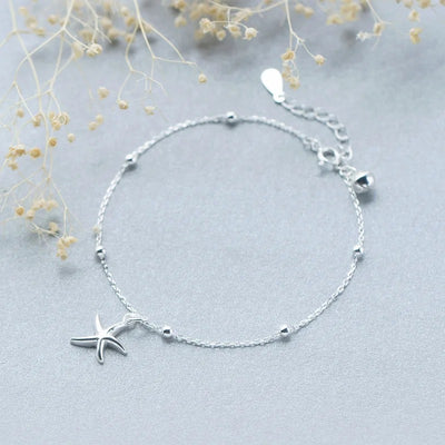 Ariel Starfish Charm Bracelet - A very delicate silver-coloured chain bracelet adorned with a tiny starfish charm and a cute little bell.