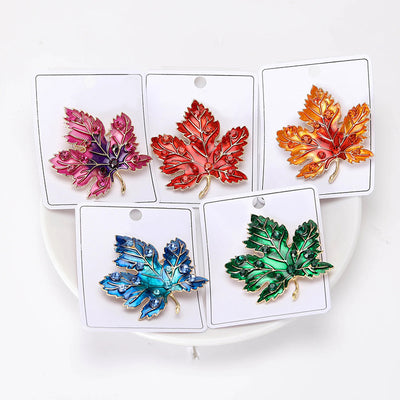 Aurelia Maple Leaf Enamel Brooch - A large, colourful enamel brooch shaped like a stylised maple leaf, studded with coloured crystals and metallic enamel paint.