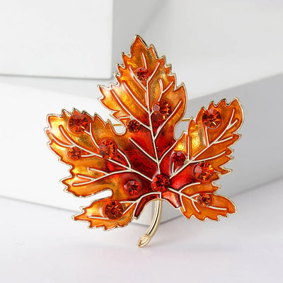 Aurelia Maple Leaf Enamel Brooch - A large, colourful enamel brooch shaped like a stylised maple leaf, studded with coloured crystals and metallic enamel paint.