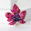 Aurelia Maple Leaf Enamel Brooch - A large, colourful enamel brooch shaped like a stylised maple leaf, studded with coloured crystals and metallic enamel paint.