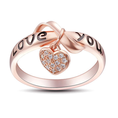 Be Still My Heart Ring - A rose gold ring with a heart and ribbon theme.