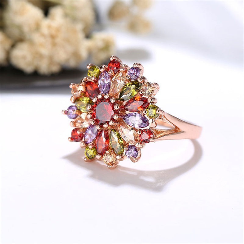 Bijoux Kaleidoscope Statement Ring - A large, circular cocktail ring with multi-coloured crystals set around a central hub, resembling a flower or burst of colour.
