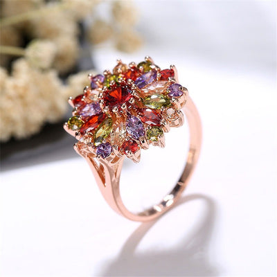 Bijoux Kaleidoscope Statement Ring - A large, circular cocktail ring with multi-coloured crystals set around a central hub, resembling a flower or burst of colour.