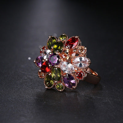 Bijoux Kaleidoscope Statement Ring - A large, circular cocktail ring with multi-coloured crystals set around a central hub, resembling a flower or burst of colour.