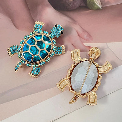 Caspia Crystal Turtle Brooch - A large stylised turtle brooch, composed of a single large, oval-shaped crystal encased in a shell of golden-coloured metal, and surrounded by lots of tiny matching crystals.