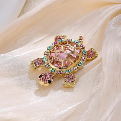 Caspia Crystal Turtle Brooch - A large stylised turtle brooch, composed of a single large, oval-shaped crystal encased in a shell of golden-coloured metal, and surrounded by lots of tiny matching crystals.