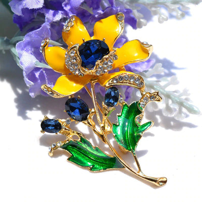 Citrika Orange Blossom Brooch - A detailed floral brooch featuring a large central stone with ruffled enamel petals surrounding it, and lots of colourful crystals to really make it pop.