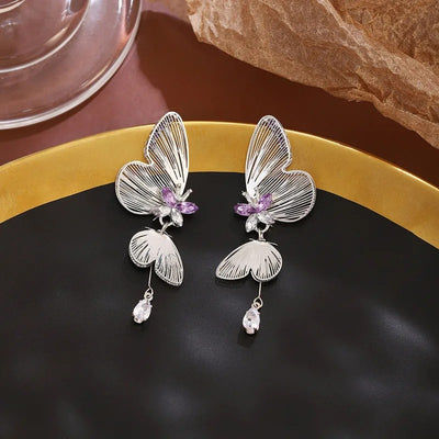 The Cynthia Butterfly Crystal Earrings - Sparkling silver butterfly wing earrings with purple and white crystals.