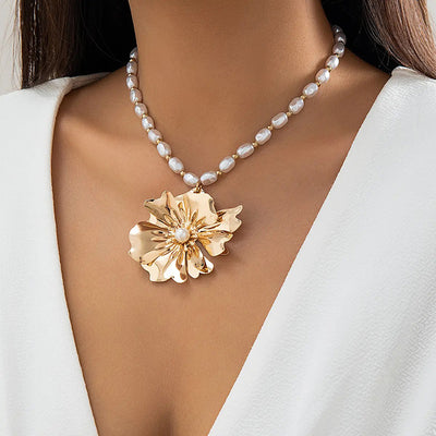 Ebele Oversized Flower Necklace - A strand of elegant oval-shaped pearls, with a large golden-coloured stylised flower pendant.