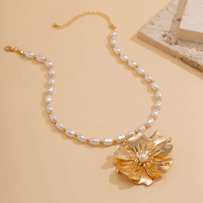 Ebele Oversized Flower Necklace - A strand of elegant oval-shaped pearls, with a large golden-coloured stylised flower pendant.