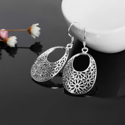 Emmaline Cut-Out Dangle Earrings - Delicate oval-shaped silver earrings with a floral cut-out pattern.