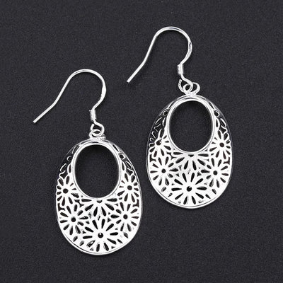 Emmaline Cut-Out Dangle Earrings - Delicate oval-shaped silver earrings with a floral cut-out pattern.