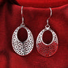 Emmaline Cut-Out Dangle Earrings - Delicate oval-shaped silver earrings with a floral cut-out pattern.