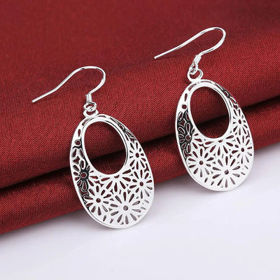 Emmaline Cut-Out Dangle Earrings - Delicate oval-shaped silver earrings with a floral cut-out pattern.