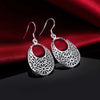 Emmaline Cut-Out Dangle Earrings - Delicate oval-shaped silver earrings with a floral cut-out pattern.