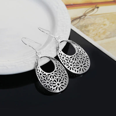 Emmaline Cut-Out Dangle Earrings - Delicate oval-shaped silver earrings with a floral cut-out pattern.