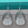 Emmaline Cut-Out Dangle Earrings - Delicate oval-shaped silver earrings with a floral cut-out pattern.