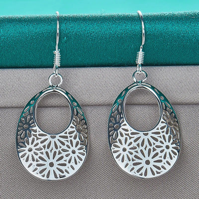 Emmaline Cut-Out Dangle Earrings - Delicate oval-shaped silver earrings with a floral cut-out pattern.