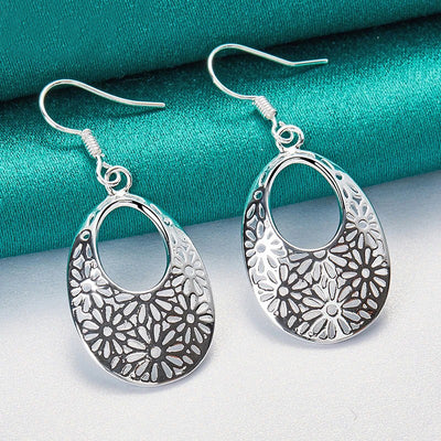 Emmaline Cut-Out Dangle Earrings - Delicate oval-shaped silver earrings with a floral cut-out pattern.