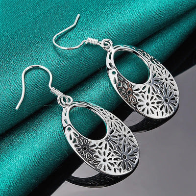 Emmaline Cut-Out Dangle Earrings - Delicate oval-shaped silver earrings with a floral cut-out pattern.