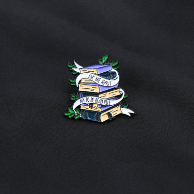 The "Ask Me About My To Be Read Pile" Enamel Pin features a pile of navy blue and purple books wrapped in a ribbon encouraging people to ask about your darkest secret... just how many books are left in your TBR pile. Oh, the shame! The shame! So many books, so little time!