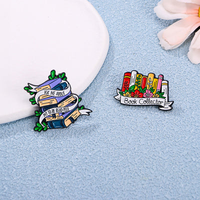 The "Ask Me About My To Be Read Pile" Enamel Pin features a pile of navy blue and purple books wrapped in a ribbon encouraging people to ask about your darkest secret... just how many books are left in your TBR pile. Oh, the shame! The shame! So many books, so little time!