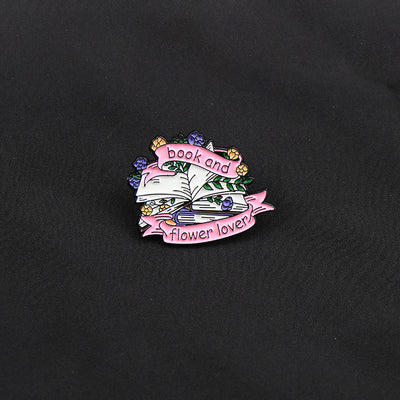 The "Book And Flower Lover" Enamel Pin is a tiny, but very stylish enamel pin, featuring a pile of stylised books wreathed in flowers and ribbons, along with simple letters proclaiming your love of said books and flowers. So cute! Grab yours today!