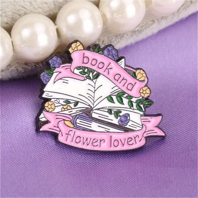The "Book And Flower Lover" Enamel Pin is a tiny, but very stylish enamel pin, featuring a pile of stylised books wreathed in flowers and ribbons, along with simple letters proclaiming your love of said books and flowers. So cute! Grab yours today!