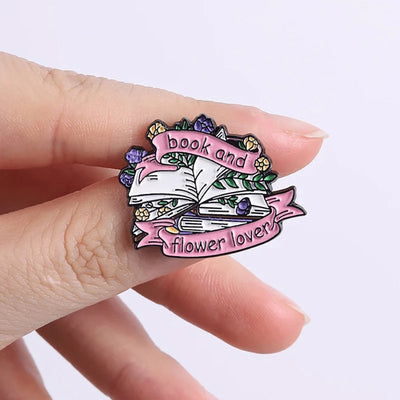 The "Book And Flower Lover" Enamel Pin is a tiny, but very stylish enamel pin, featuring a pile of stylised books wreathed in flowers and ribbons, along with simple letters proclaiming your love of said books and flowers. So cute! Grab yours today!