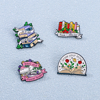 The "Book And Flower Lover" Enamel Pin is a tiny, but very stylish enamel pin, featuring a pile of stylised books wreathed in flowers and ribbons, along with simple letters proclaiming your love of said books and flowers. So cute! Grab yours today!
