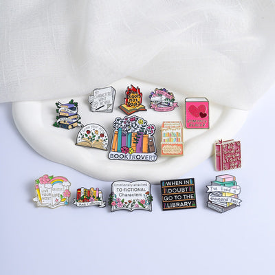 The "Book And Flower Lover" Enamel Pin is a tiny, but very stylish enamel pin, featuring a pile of stylised books wreathed in flowers and ribbons, along with simple letters proclaiming your love of said books and flowers. So cute! Grab yours today!