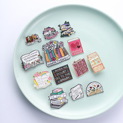 The "Book And Flower Lover" Enamel Pin is a tiny, but very stylish enamel pin, featuring a pile of stylised books wreathed in flowers and ribbons, along with simple letters proclaiming your love of said books and flowers. So cute! Grab yours today!