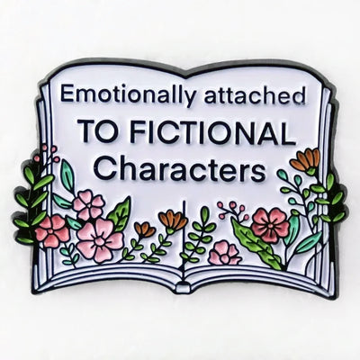 The "Emotionally Attached To Fictional Characters" Enamel Pin features a stylised book adorned with delicate leaves and flowers, and text proclaiming your love of certain fictional characters. Oh my! No judgement here!