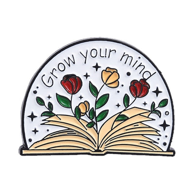 The "Grow Your Mind" Enamel Pin an average-sized brooch featuring a stylised book with flowers and vines sprouting from the pages, and text encouraging you to grow your mind. So true!