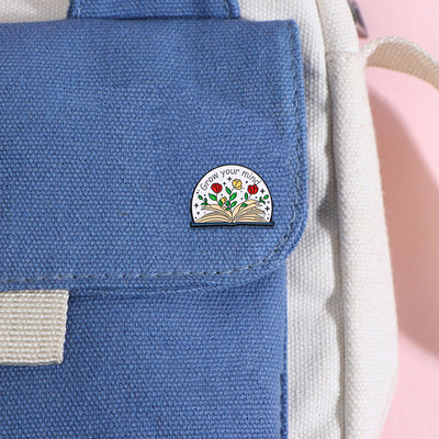 The "Grow Your Mind" Enamel Pin an average-sized brooch featuring a stylised book with flowers and vines sprouting from the pages, and text encouraging you to grow your mind. So true!