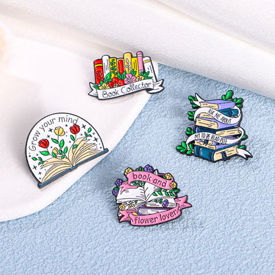 The "Grow Your Mind" Enamel Pin an average-sized brooch featuring a stylised book with flowers and vines sprouting from the pages, and text encouraging you to grow your mind. So true!
