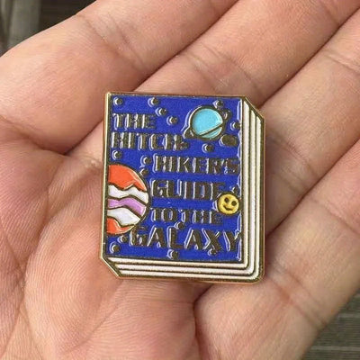 The "Hitchhiker's Guider" Enamel Pin features a stylised replica of the cult classic book, The Hitchhiker's Guide To The Galaxy, in vibrant coloured enamel paint, edged with metallic gold.