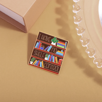 The "I Have No Shelf Control" Enamel Pin features a stylised bookshelf with large text proclaiming that you have no shelf control. So true.