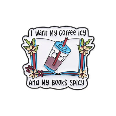 The "I Want My Coffee Icy And My Books Spicy" Enamel Pin features a stylised cup of iced coffee atop a book, adorned with colourful flowers and leaves.