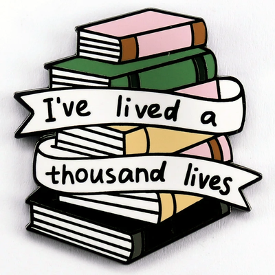 The "I've Lived A Thousand Lives" Enamel Pin features a stack of colourful stylised cartoon books, with a ribbon on the front announcing just how many fantastical lives you've lived. At least a thousand! Maybe more!