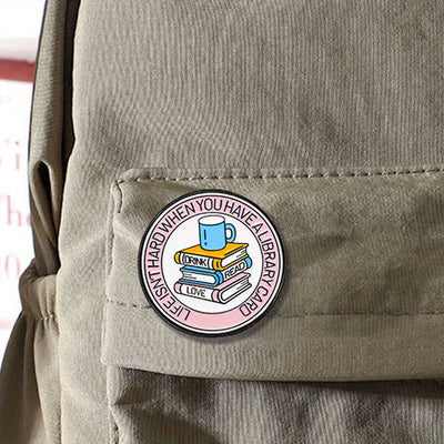 The "Life Isn't Hard When You Have A Library Card" Enamel Pin features a stack of books in the centre (plus a cup of sweet, sweet coffee!), within a ring of text proclaiming your love for libraries.