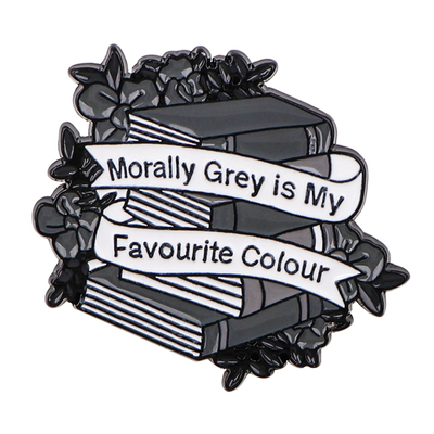 The "Morally Grey Is My Favourite Colour" Enamel Pin cool, stylised pin featuring a stack of stylised books with different shades of grey covers and a ribbon woven around them featuring the slogan.