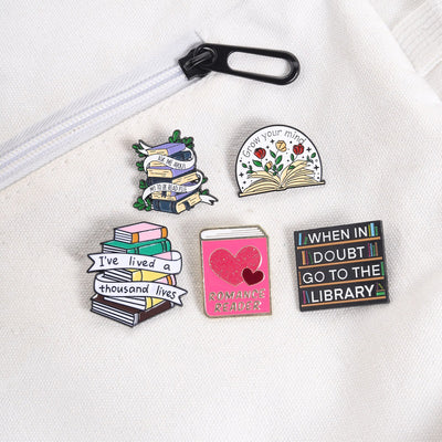 The "Romance Reader" Enamel Pin is a simple but elegant design, featuring a pink book outlined in gold, adorned with hearts. Perfect for expressing your love of the romance genre to all. Grab yours today!