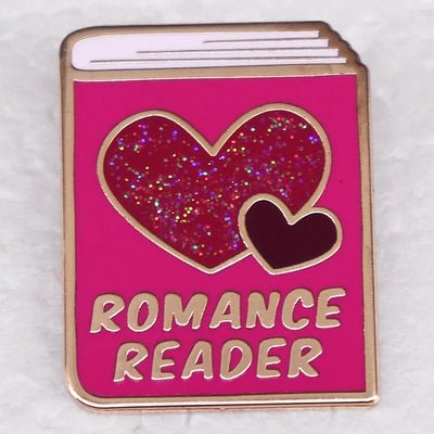 The "Romance Reader" Enamel Pin is a simple but elegant design, featuring a pink book outlined in gold, adorned with hearts. Perfect for expressing your love of the romance genre to all. Grab yours today!
