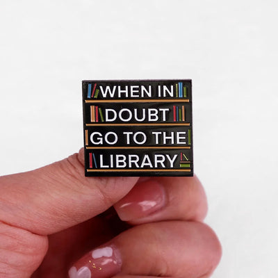 The "When In Doubt Go To The Library" Enamel Pin a large pin featuring a stylised bookshelf covered in books, and lettering proclaiming your love of all things library-related.