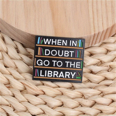The "When In Doubt Go To The Library" Enamel Pin a large pin featuring a stylised bookshelf covered in books, and lettering proclaiming your love of all things library-related.