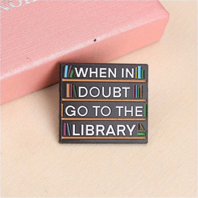 The "When In Doubt Go To The Library" Enamel Pin a large pin featuring a stylised bookshelf covered in books, and lettering proclaiming your love of all things library-related.
